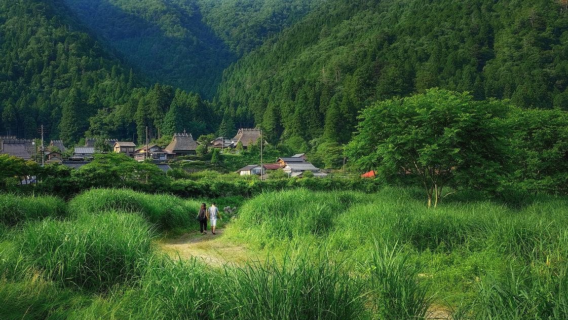 local minibus driving through rural Sichuan countryside, small village in distance, traditional architecture, scenic route