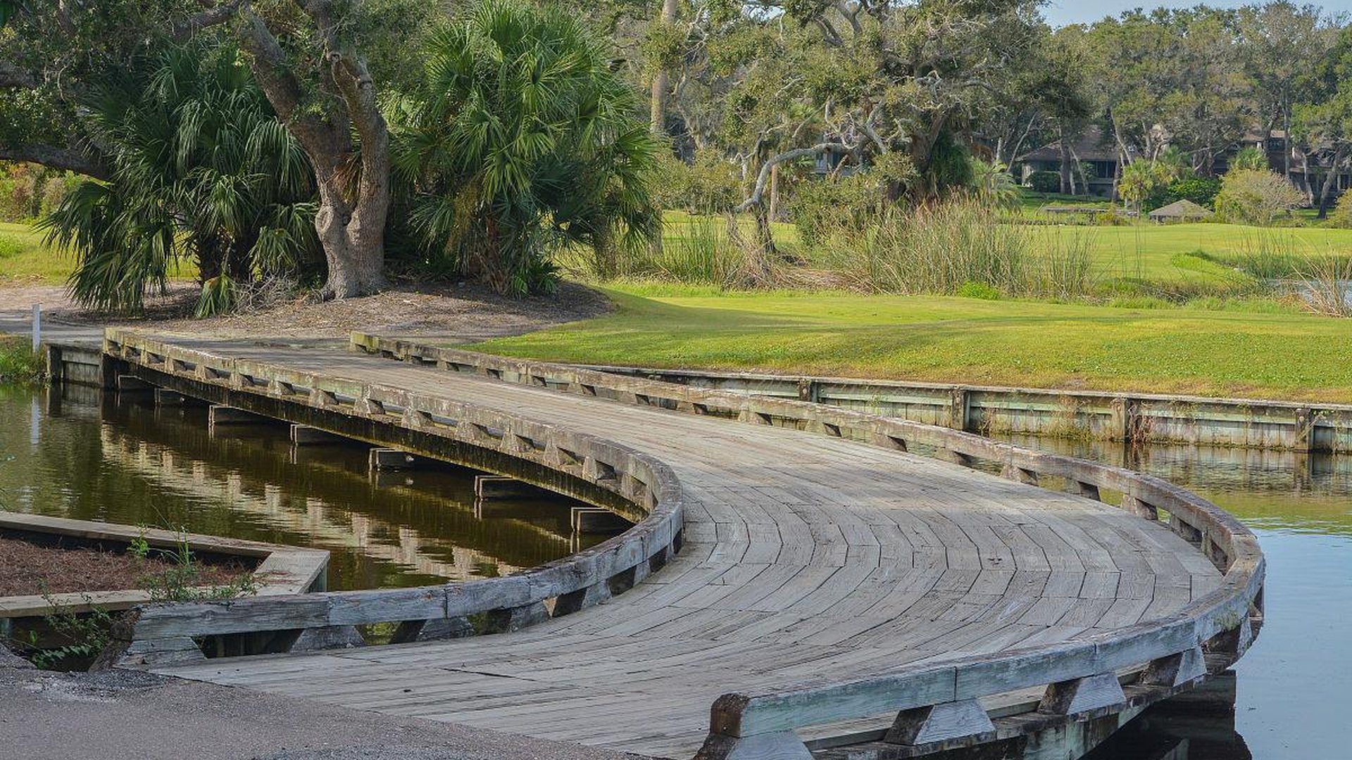 traveler sitting on a small wooden bridge in a countryside village, notebook and camera nearby, peaceful rural landscape, golden hour lighting