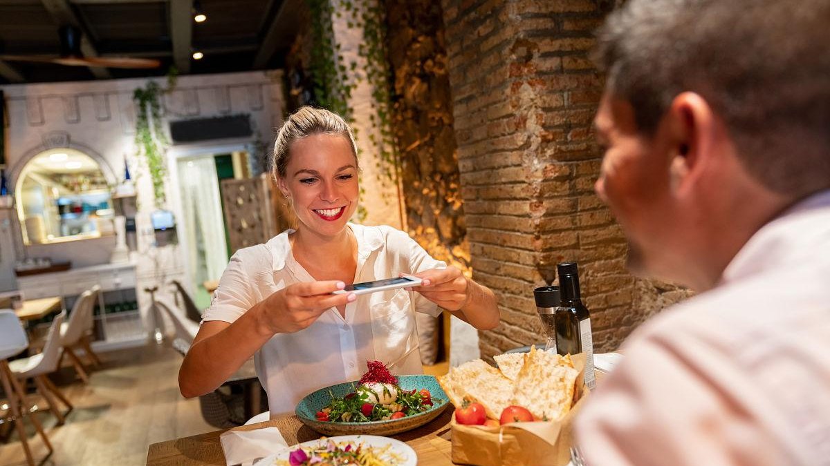 woman from Chicago smiling while tasting street food with local vendor in small alley