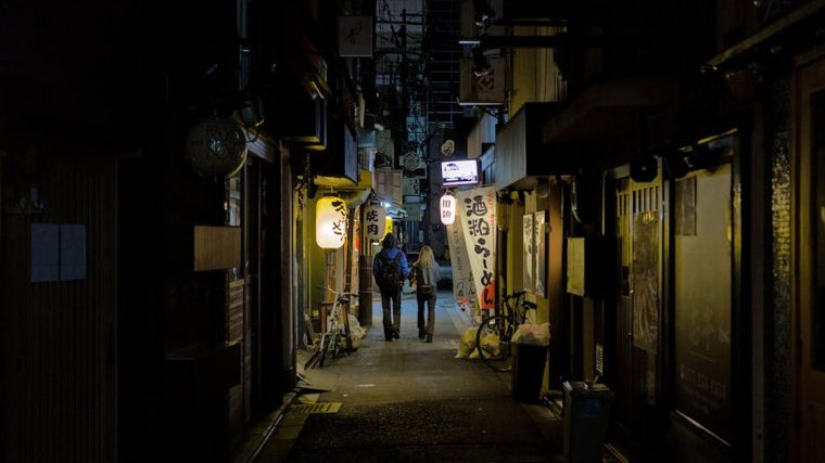 A traveler walks down a crowded city sidewalk into a quiet